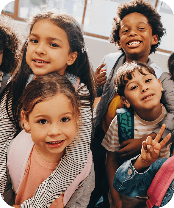Smiling children with backpacks in classroom.