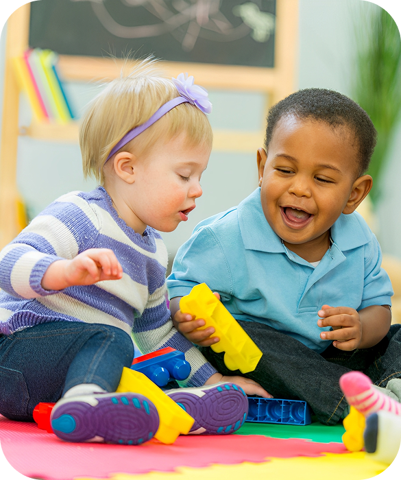 Two toddlers playing with colorful blocks.
