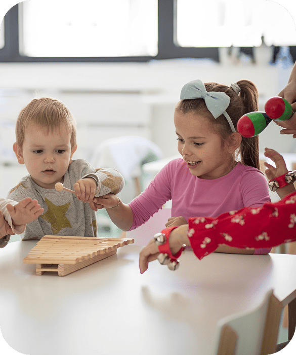 Children playing with musical instruments in classroom.