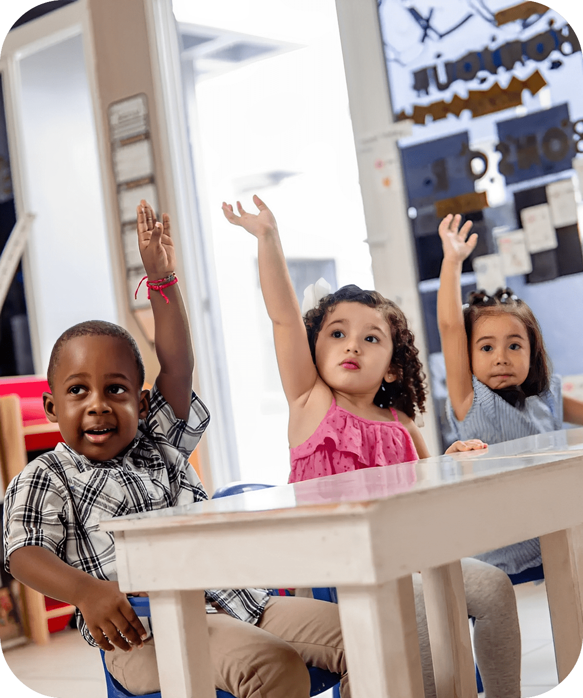 Children raising hands in a classroom setting.